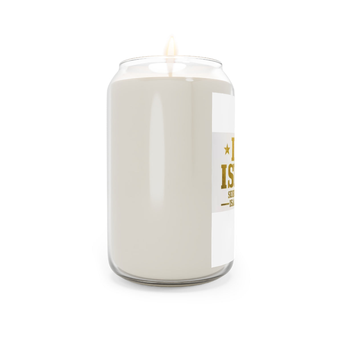 A lit candle in a clear glass jar with a white wax body and a white label gold text , shown against a plain white background 